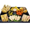 Black eight-compartment catering platter filled with sandwiches, wraps, fruit and dip pots