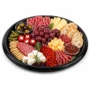 Black round platter filled with cheeses, charcuterie, grapes, crackers and small dip pots