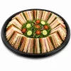 Black round platter base filled with triangular sandwiches and salad